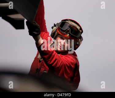 A sailor conducts a pre-flight inspection on an aircraft aboard the ...