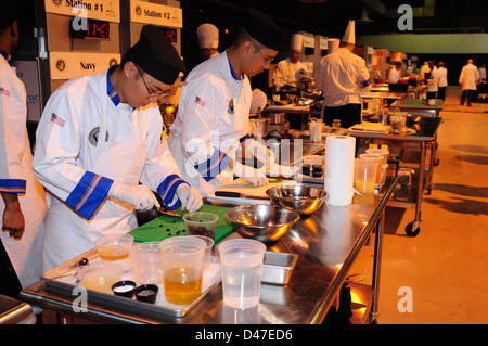 A Sailor chops vegetables during the 37th annual Military Culinary Arts Competition, showcasing culinary skills and precision. The competition highlights the expertise of military chefs in preparing meals under pressure, emphasizing teamwork and culinary techniques in a professional setting. Stock Photo