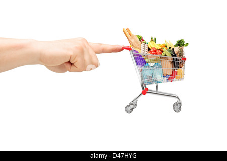 Finger pushing a shopping cart full of food products, isolated on white background Stock Photo