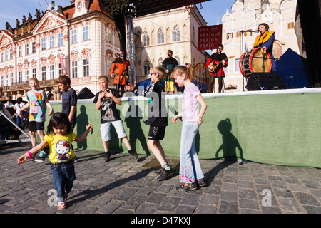 Children dancing funny by the Easter Market stage where medieval music band Bakchus is performing. Old Town Square. Prague Stock Photo
