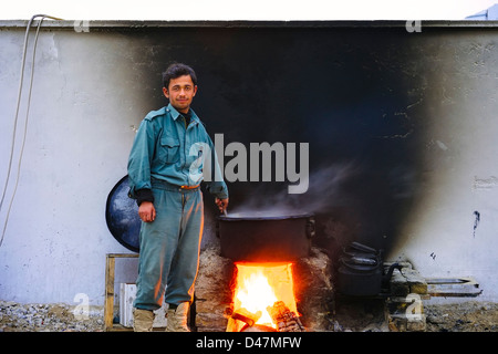 Kandahar, Afghanistan - January 10, 2011:  An Afghan Policeman cooks dinner for his squad on a cold winter evening. Stock Photo