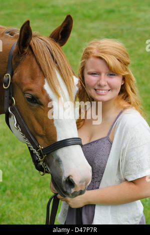 Smiling girl with her horse in portrait, head shot of a red haired teenager and her animal. Stock Photo