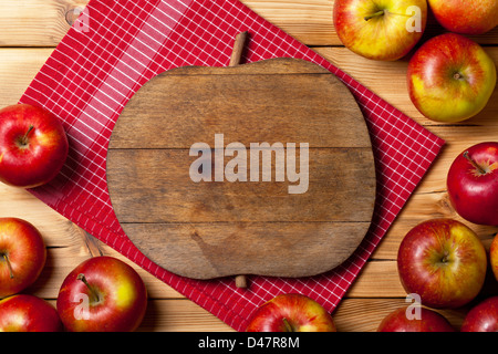 Fresh apples on wooden background. Composition with fruits and cutting board with apple shape. Copy space Stock Photo