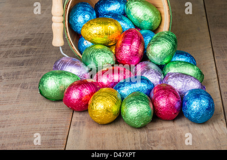 A wicker basket spilling foil Easter eggs Stock Photo