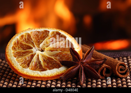 orange slice with anis and cinamon sticks on bamboo mat in front of fireplace Stock Photo