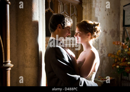 Bride and groom embrace looking into each others eyes inside stone church building Stock Photo