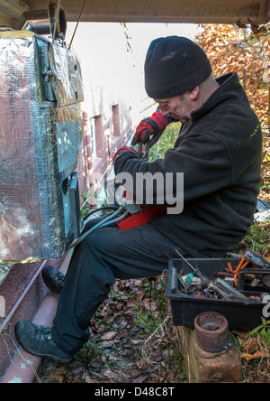 SERVICE ENGINEER SERVICING CENTRAL HEATING OIL-FIRED BOILER IN GARDEN UK, Stock Photo