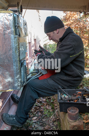 SERVICE ENGINEER SERVICING CENTRAL HEATING OIL-FIRED BOILER IN GARDEN UK, Stock Photo