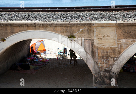 People in Day Out At Kalk Bay Beach find shade under Railway Arches - Western Cape - South Africa Stock Photo