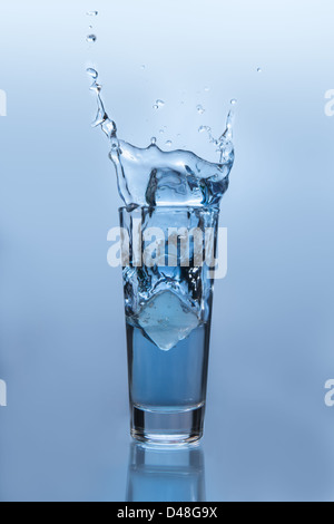 Ice cube falling into glass of water Stock Photo - Alamy