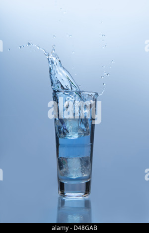 Ice cube falling into glass of water Stock Photo - Alamy
