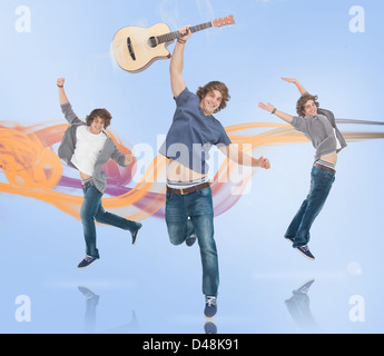 Three of the same young man jumping for joy one holding a guitar Stock Photo