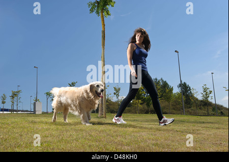 Young woman walking a Golden Retriever dog Stock Photo