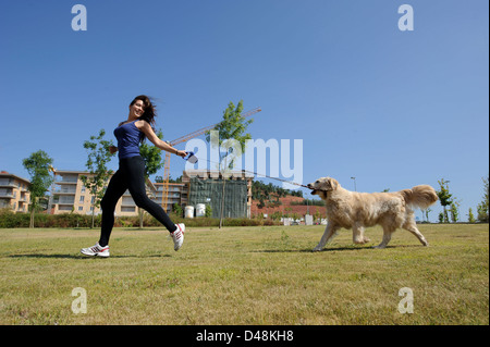 Young woman running with a Golden Retriever dog Stock Photo