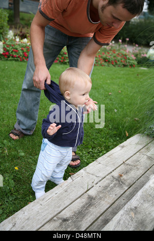 Toddler learning to walk, father helping Stock Photo