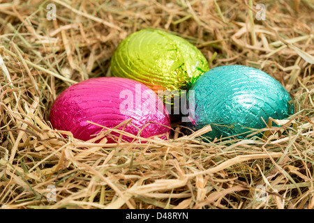 Three colouful easter eggs nestled in straw nest Stock Photo