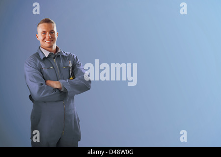 Mechanic standing in front of a blue background Stock Photo