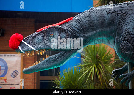 Bournemouth, UK. 8th March 2013. COMEDY Darren the dinosaur is released onto the streets of Bournemouth in aid of Comic Relief. Darren the dinosaur is three metres tall by eight metres long and was used in Walking with Dinosaurs, He was set free by celebrity Chris Jarvis from outside the BIC. The event was organised by Sainsbury's to encourage people to call into any store to get their red noses to protect themselves should they see the prehistoric creature while out and about. Credit:  Carolyn Jenkins / Alamy Live News Stock Photo