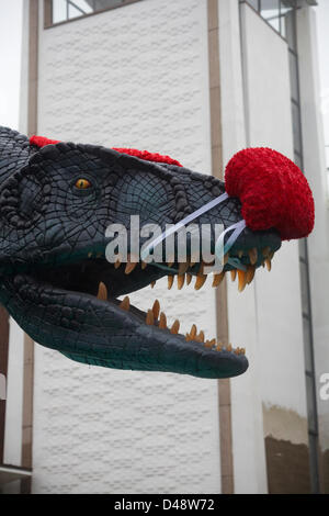 Bournemouth, UK. 8th March 2013. COMEDY Darren the dinosaur is released onto the streets of Bournemouth in aid of Comic Relief. Darren the dinosaur is three metres tall by eight metres long and was used in Walking with Dinosaurs, He was set free by celebrity Chris Jarvis from outside the BIC. The event was organised by Sainsbury's to encourage people to call into any store to get their red noses to protect themselves should they see the prehistoric creature while out and about. Credit:  Carolyn Jenkins / Alamy Live News Stock Photo