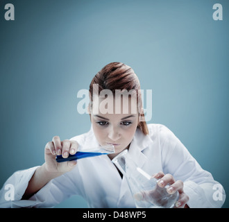 Blonde scientist pouring liquid into erlenmeyer Stock Photo