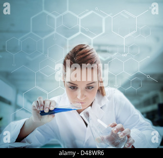 Scientist pouring liquid into erlenmeyer with futuristic screen showing formula Stock Photo
