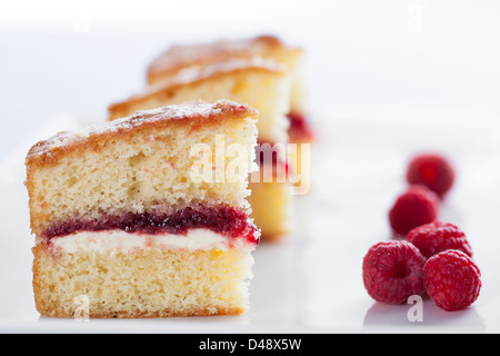 Victoria sponge cake with cream and jam filling, served with raspberries Stock Photo