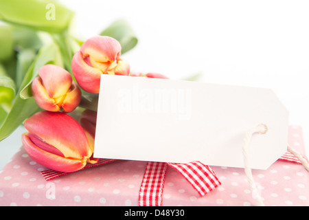 Bouquet of beautiful tulips next to a gift with an empty card Stock Photo