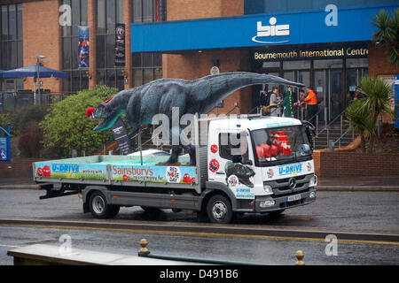 Bournemouth, UK. 8th March 2013. COMEDY Darren the dinosaur is released onto the streets of Bournemouth in aid of Comic Relief. Darren the dinosaur is three metres tall by eight metres long and was used in Walking with Dinosaurs, He was set free by celebrity Chris Jarvis from outside the BIC. The event was organised by Sainsbury's to encourage people to call into any store to get their red noses to protect themselves should they see the prehistoric creature while out and about. Credit:  Carolyn Jenkins / Alamy Live News Stock Photo