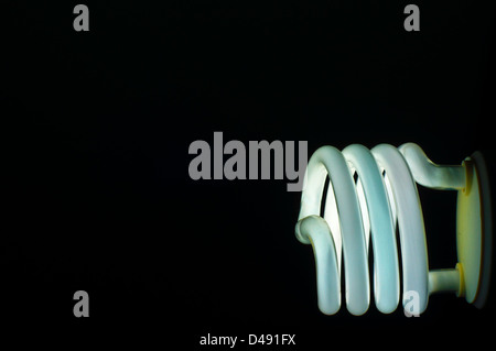 A lit light bulb set against a black background. Stock Photo