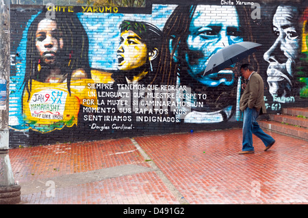 A man walking by graffiti in the rain in Bogota, Colombia Stock Photo