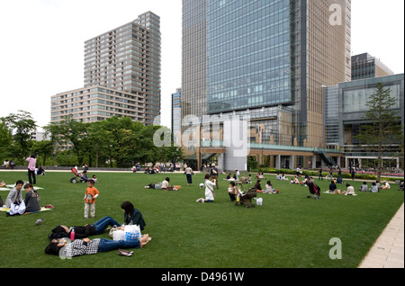 People relaxing on lawn at new, modern Tokyo Midtown, a mixed-use shopping, hotel and residential complex in Roppongi, Tokyo Stock Photo