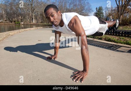 A strong young African American man working out outdoors in a park Stock Photo
