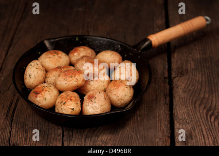 Roasted potatoes with sea salt and herbs in pan on rustic table Stock Photo