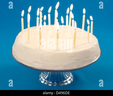 Birthday cake with burning candles on blue background Stock Photo