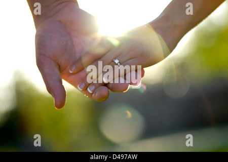 Closeup photo of an engaged couple holding hands showing engagement ring. Stock Photo