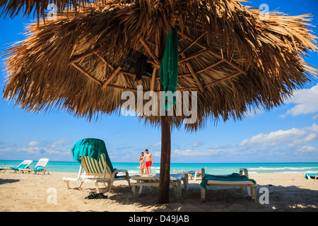 beach hut, chairs and towels with a couple walking on the beach Stock Photo