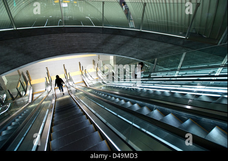 A modern architectural interior at an underground subway escalator moves commuters to the train platform in Shibuya, Tokyo.