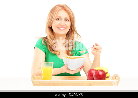 Smiling woman eating cereals and fruit for breakfast isolated on white background Stock Photo