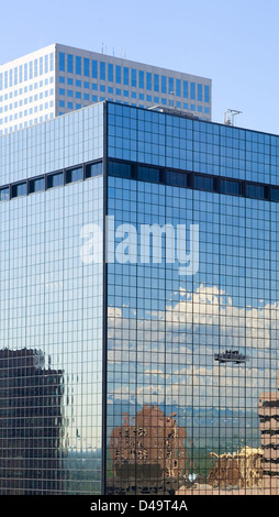 Two laborers wash the windows of a skyscraper with the reflection of mountains and clouds in the background Stock Photo