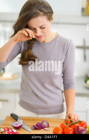 Young housewife crying while cutting onion Stock Photo