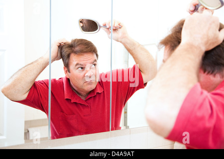 Middle aged man looking for bald spots in the mirror.  Stock Photo