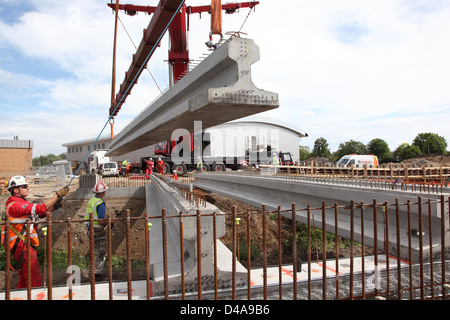 17m long pre-stressed concrete beams are lowered into place to support a new road bridge spanning a river culvert in Woking, UK Stock Photo