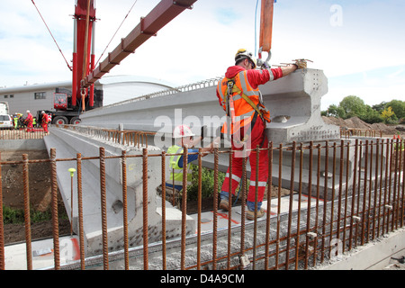 17m long pre-stressed concrete beams are lowered into place to support a new road bridge spanning a river culvert in Woking, UK Stock Photo