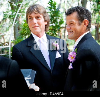 Handsome gay couple getting married in outdoor ceremony. Stock Photo