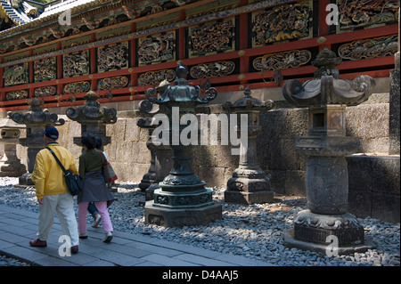 Visitors pass by the ornate Tozai Kairo carved nature scene and wildlife panel wall at the Toshogu Jinja Shrine in Nikko, Japan Stock Photo