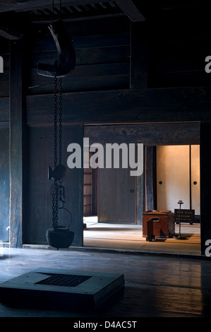 Historic village folk house interior with irori fire pit and jizaikagi hanging iron kettle with fish-shaped height adjuster Stock Photo