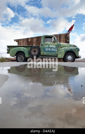 An old pickup parked by Route 66, blue sky reflected in the water. Stock Photo