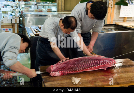 Fishmongers cutting up a large fresh tuna at Tsukiji Wholesale Fish Market, the world's largest fish market in Tokyo, Japan. Stock Photo