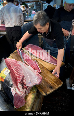 A fishmonger slices up a large fresh tuna with a sharp knife at Tsukiji Wholesale Fish Market in Tokyo Stock Photo