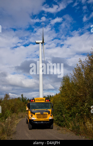 School bus in front of a huge wind-turbine . Stock Photo